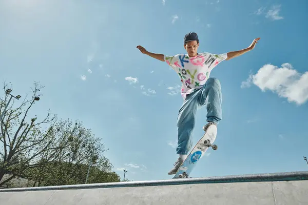 Un joven skater monta con confianza su monopatín por una empinada rampa en un parque de skate en un soleado día de verano.. - foto de stock
