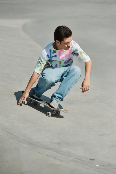 Молодий чоловік виконує трюки на бетоні на скейтборді в сонячному скейт-парку. — стокове фото