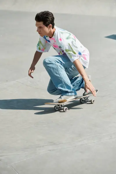 Un jeune homme chevauchant en toute confiance une planche à roulettes sur une rampe de ciment dans un skate park par une journée d'été ensoleillée. — Photo de stock