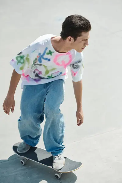 Un niño monta hábilmente su monopatín en la superficie lisa de cemento de un parque de skate en un día soleado de verano.. - foto de stock
