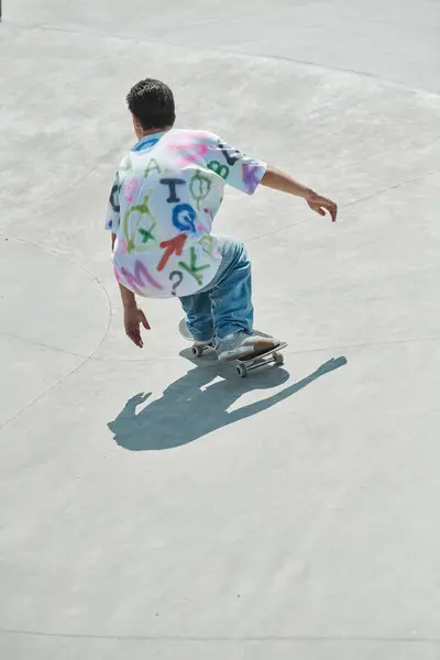 Un giovane skater boy guida con sicurezza uno skateboard lungo una rampa di cemento in un vivace skate park all'aperto in una giornata estiva soleggiata. — Foto stock
