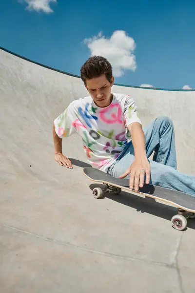 Ein junger Skater-Junge hält an einem sonnigen Sommertag sein Skateboard in der Rampe des Skateparks. — Stockfoto