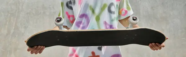 Молодий ковзаняр тримає скейтборд на відкритому повітрі в сонячному скейт-парку, готуючись до захоплюючої поїздки в літній день. — стокове фото