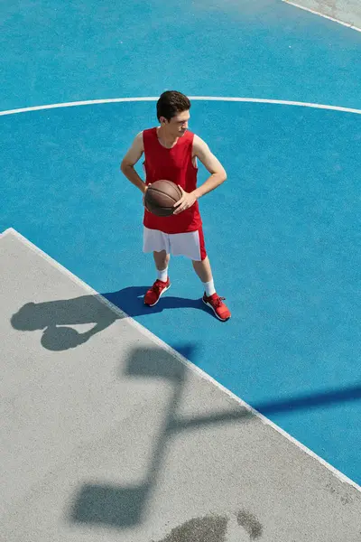 Талановитий молодий чоловік впевнено тримає баскетбол, стоячи на дворі, відточуючи свої навички — стокове фото