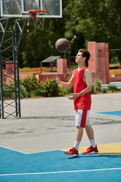 Молодой человек капает баскетбольный мяч на солнечной площадке, демонстрируя свои навыки и страсть к игре. — стоковое фото