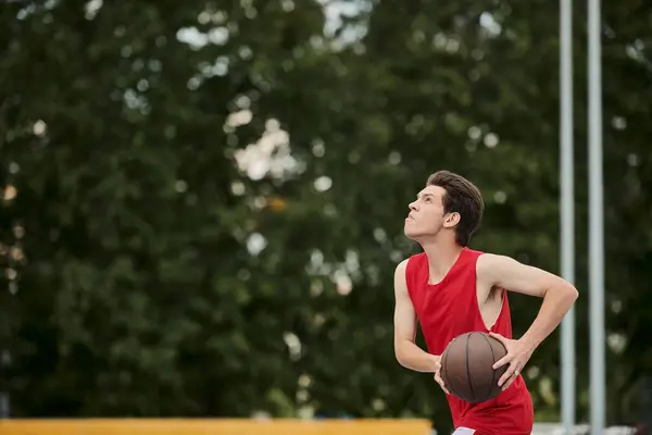 Un joven corre en un campo, sosteniendo una pelota de baloncesto en un día de verano. - foto de stock