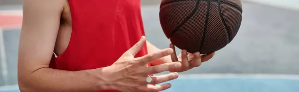 Молодой баскетболист держит мяч в руке, готовый играть на открытом воздухе в летний день. — стоковое фото