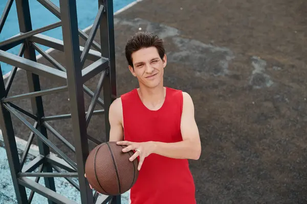 Яскраве зображення з молодим баскетболістом у червоній сорочці, вміло обробляючи баскетбол на відкритому повітрі в сонячний день. — стокове фото