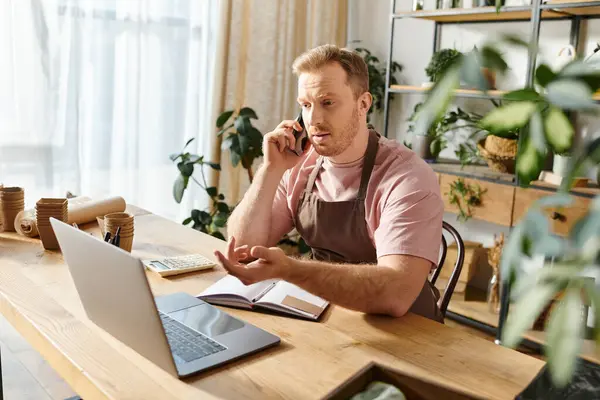 Ein Mann mit Laptop, der sich auf seine Arbeit in einem Pflanzengeschäft konzentriert, verkörpert den Geist des Unternehmertums und des Engagements. — Stockfoto