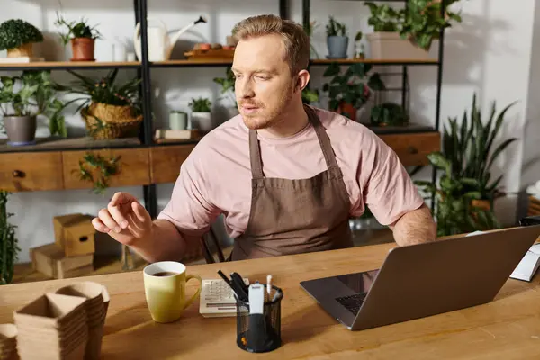 Um homem focado em seu laptop, imerso em suas operações de pequenos negócios em uma loja de plantas. — Fotografia de Stock