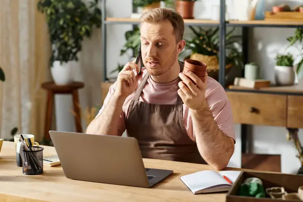Um homem com um laptop sentado em uma mesa em uma loja de plantas, mostrando a essência da propriedade de pequenas empresas e empreendedorismo. — Fotografia de Stock