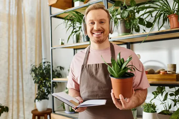 A man cradles a potted plant and a notebook in his hands, embodying the harmony between knowledge and nature. — Stock Photo