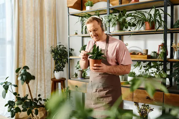 Ein Mann hält anmutig eine Topfpflanze in einem gemütlichen Wohnzimmer und verleiht dem Innenraum einen Hauch von Natur. — Stockfoto