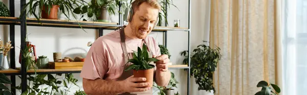 Ein Mann hält zart eine Topfpflanze in den Händen und zeigt in seinem kleinen Geschäft Sorgfalt und Leidenschaft für die Gartenarbeit. — Stockfoto