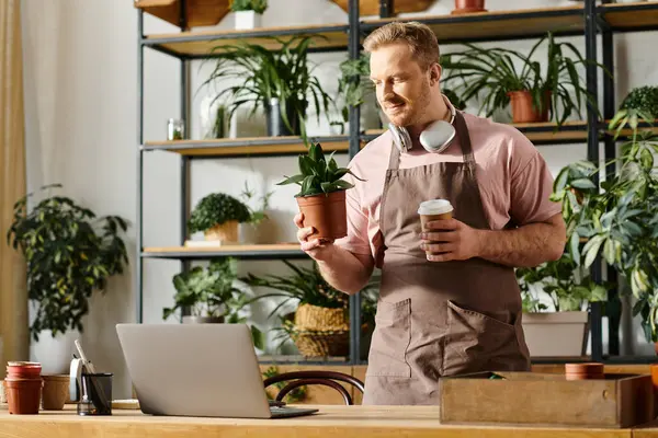 Ein Mann in Schürze genießt eine Tasse Kaffee in einem Pflanzenladen. — Stockfoto