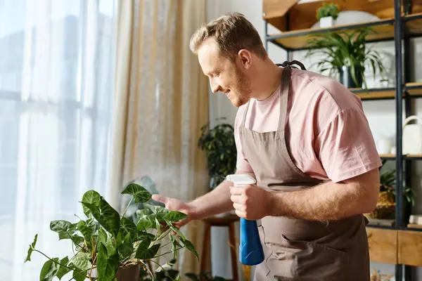 Un hombre sosteniendo una taza de café frente a una planta en maceta. - foto de stock