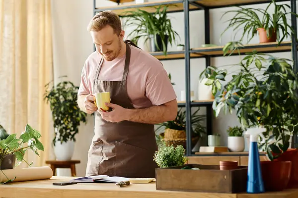 Ein gutaussehender Mann in Schürze entspannt sich und hält eine dampfende Tasse Kaffee in der Hand. — Stockfoto