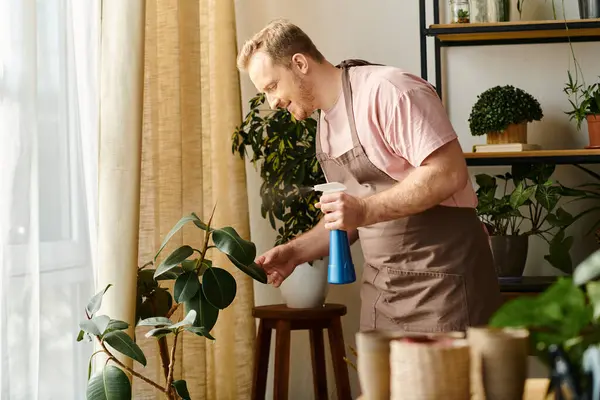 Un homme dans un tablier nettoie méticuleusement une plante en pot dans un petit magasin de plantes, incarnant le soin et l'attention aux détails. — Photo de stock