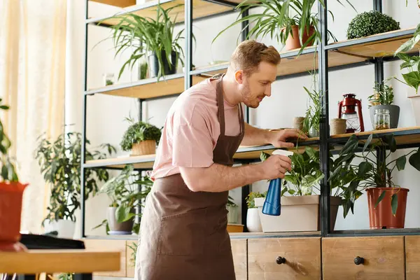 A man in an apron lovingly tends to his plants, creating a lush oasis in his own plant shop. — Stock Photo