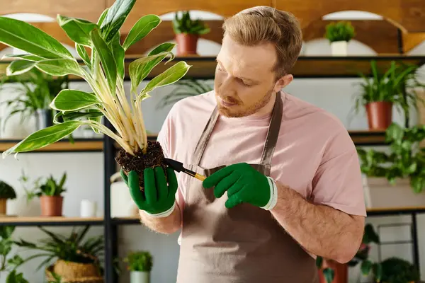 Ein Mann hält eine Pflanze in der Hand und zeigt in einem Pflanzenladen Sorgfalt und Verbundenheit mit der Natur. — Stockfoto