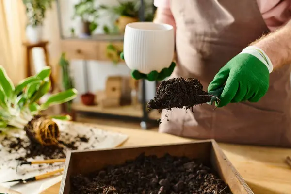 Uma pessoa com luvas verdes delicadamente mantém uma planta em uma caixa, incorporando cuidado e conexão com a natureza em um ambiente de pequenas empresas.. — Fotografia de Stock