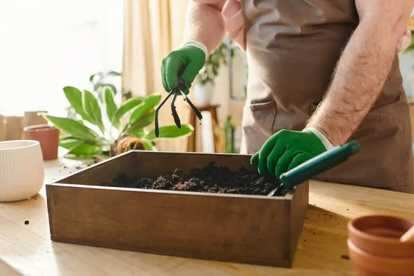 Une personne en gants nettoyant méticuleusement une boîte dans un magasin de plantes, incarnant le dévouement de posséder une petite entreprise. — Photo de stock