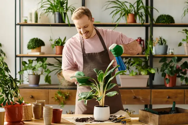 Un hombre en un delantal está regando delicadamente una planta en maceta, nutriéndola con amor y atención en un acogedor entorno de tienda de plantas. - foto de stock