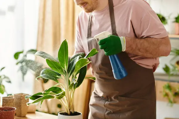 Um homem em um avental limpa delicadamente uma planta em vaso em uma pequena loja, incorporando a essência de nutrir e cuidar. — Fotografia de Stock