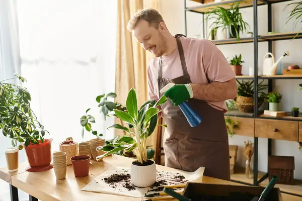 Un hombre atiende a una planta en maceta sobre una mesa en una pequeña tienda de plantas, ilustrando el cuidado y el crecimiento en un entorno floral. - foto de stock