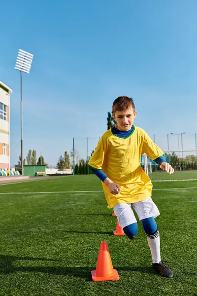 Un ragazzo abile prende a calci appassionatamente un pallone da calcio intorno a un cono, dimostrando un controllo impressionante e agilità nei suoi movimenti sul campo.. — Foto stock