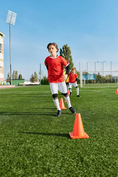 Группа маленьких детей, наполненных энергией и энтузиазмом, играющих в энергичную игру в футбол на зеленом поле. Они бегут, бьют по мячу и подбадривают друг друга под ярким солнцем. — стоковое фото