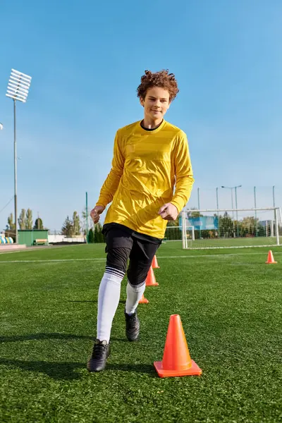 Un uomo dalla corporatura atletica, con una camicia gialla brillante, prende a calci intensamente un pallone da calcio con precisione e abilità. — Foto stock