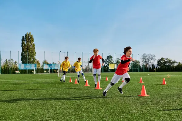 Un groupe animé de jeunes gens engagés dans un jeu animé de football, donner des coups de pied au ballon, courir à travers le terrain, et de la stratégie pour marquer des buts. — Photo de stock
