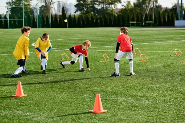 Un groupe animé de jeunes enfants jouant énergiquement à un jeu de football sur un terrain herbeux, courant, donnant des coups de pied et acclamant alors qu'ils participent à un match amical. — Photo de stock