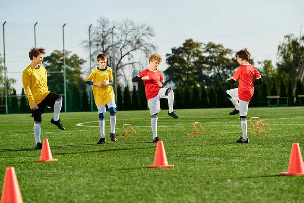 Un gruppo di giovani ragazzi con energia vibrante calcia intorno a un pallone da calcio su un campo erboso, ridendo e gareggiando in una partita amichevole. — Foto stock