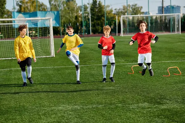 Une scène vibrante se déroule comme un groupe de jeunes garçons jouent passionnément un jeu de football. Les garçons poursuivent énergiquement le ballon, font des passes stratégiques et tentent des tirs audacieux au but dans un esprit de travail d'équipe et d'athlétisme. — Photo de stock