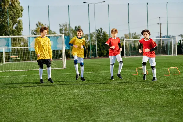 A lively group of young boys play a game of soccer, kicking the ball back and forth with enthusiasm on a grassy field. They are dressed in colorful jerseys and are focused on scoring goals while displaying teamwork and skill. — Stock Photo