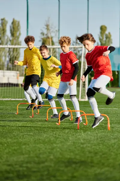 Un groupe de jeunes garçons jouant à un jeu énergique de football sur un terrain herbeux. Ils courent, donnent des coups de pied au ballon et s'encouragent mutuellement pendant qu'ils concourent. — Photo de stock