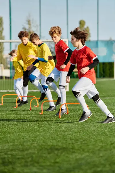 Un groupe de jeunes garçons jouant avec enthousiasme un jeu de football sur un terrain herbeux, courir, donner des coups de pied et passer le ballon avec excitation et concentration. — Photo de stock