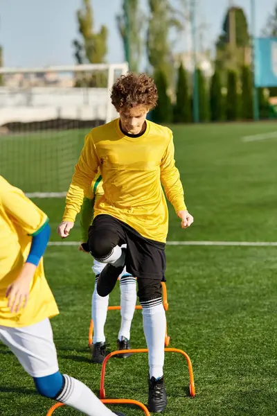 Dos jóvenes participan en un intenso juego de fútbol, mostrando sus habilidades mientras maniobran la pelota a través del campo e intentan marcar un gol.. - foto de stock