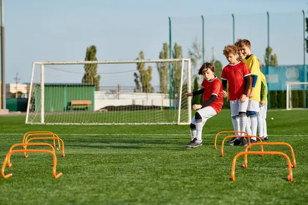 Un groupe de jeunes enfants énergiques engagés dans un jeu amical de football sur un terrain ensoleillé. Ils dribbler, passer, et tirer sur la balle, montrant le travail d'équipe et l'enthousiasme. — Photo de stock