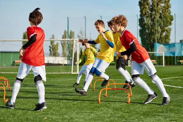 Una escena vibrante se desarrolla cuando un grupo de jóvenes juegan con entusiasmo un juego de fútbol, pateando la pelota con habilidad y energía en un campo iluminado por el sol. - foto de stock