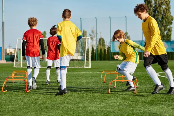 Un groupe de jeunes garçons jouent énergiquement à un jeu de football sur un terrain herbeux. Ils courent, donnent des coups de pied au ballon et s'encouragent mutuellement dans une atmosphère amicale et compétitive.. — Photo de stock
