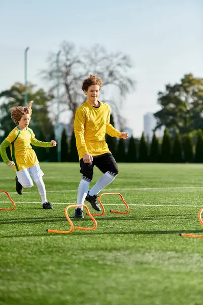 Un grupo de jóvenes que participan en un animado juego de fútbol, correr, gotear y patear la pelota con pasión y trabajo en equipo en un campo verde vibrante. - foto de stock