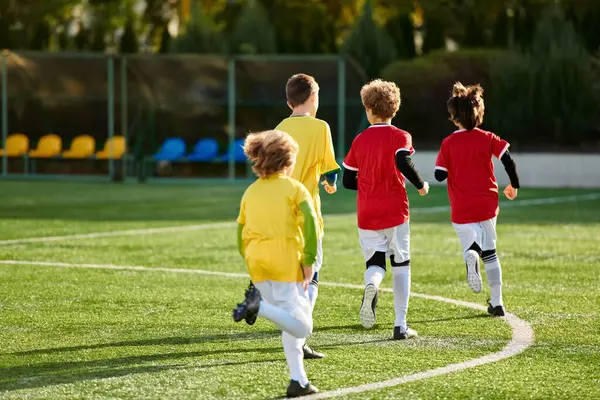 Una vivace scena di bambini che giocano a un vivace gioco di calcio, corsa, calci e tifo sul campo erboso con entusiasmo ed eccitazione. — Foto stock