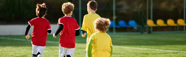 Eine Gruppe junger Jungen steht selbstbewusst auf einem Fußballplatz und blickt auf den saftig grünen Rasen darunter. Sie strotzen vor Energie und Enthusiasmus und sind bereit, das vor ihnen liegende Spiel zu gewinnen.. — Stockfoto