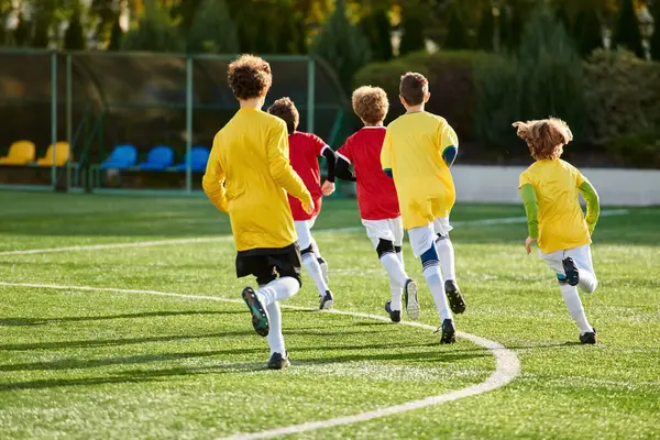 Una escena vibrante se desarrolla cuando un grupo de jóvenes juegan un juego de fútbol en un campo de hierba, pateando la pelota con entusiasmo y persiguiéndola. Su energía y camaradería crean un momento emocionante y dinámico. - foto de stock