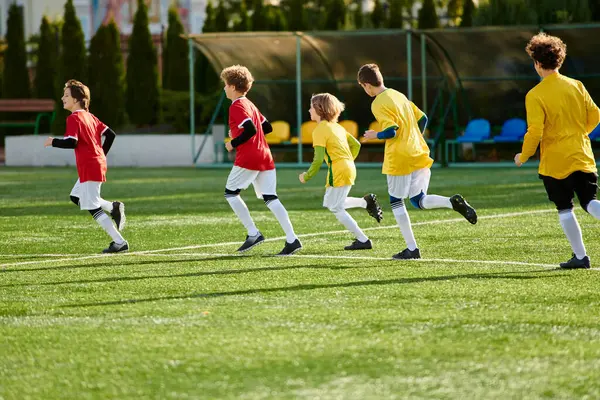 Un groupe de jeunes garçons énergiques sont plongés dans un jeu de football, dribbler et passer le ballon avec enthousiasme. Ils courent, donnent des coups de pied et crient de joie alors qu'ils concourent sur le terrain. — Photo de stock