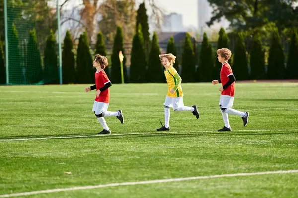 Eine Gruppe kleiner Kinder spielt voller Energie und Begeisterung Fußball. Sie rennen, treten gegen den Ball und lachen fröhlich, während sie auf einem Rasenplatz spielen.. — Stockfoto