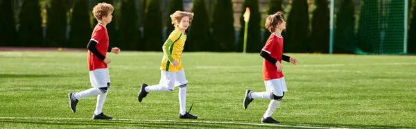Um grupo de jovens apaixonadamente jogando um jogo de futebol, correndo, chutando, e passando a bola em um campo gramado sob o sol quente. — Fotografia de Stock
